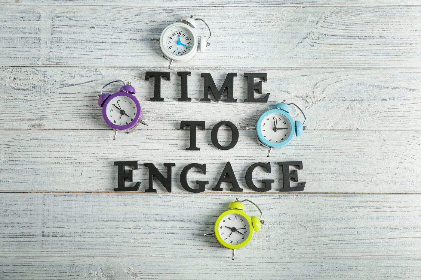 Uhren und Satz TIME TO ENGAGE (Zeit für Engagement) auf hölzernem Hintergrund