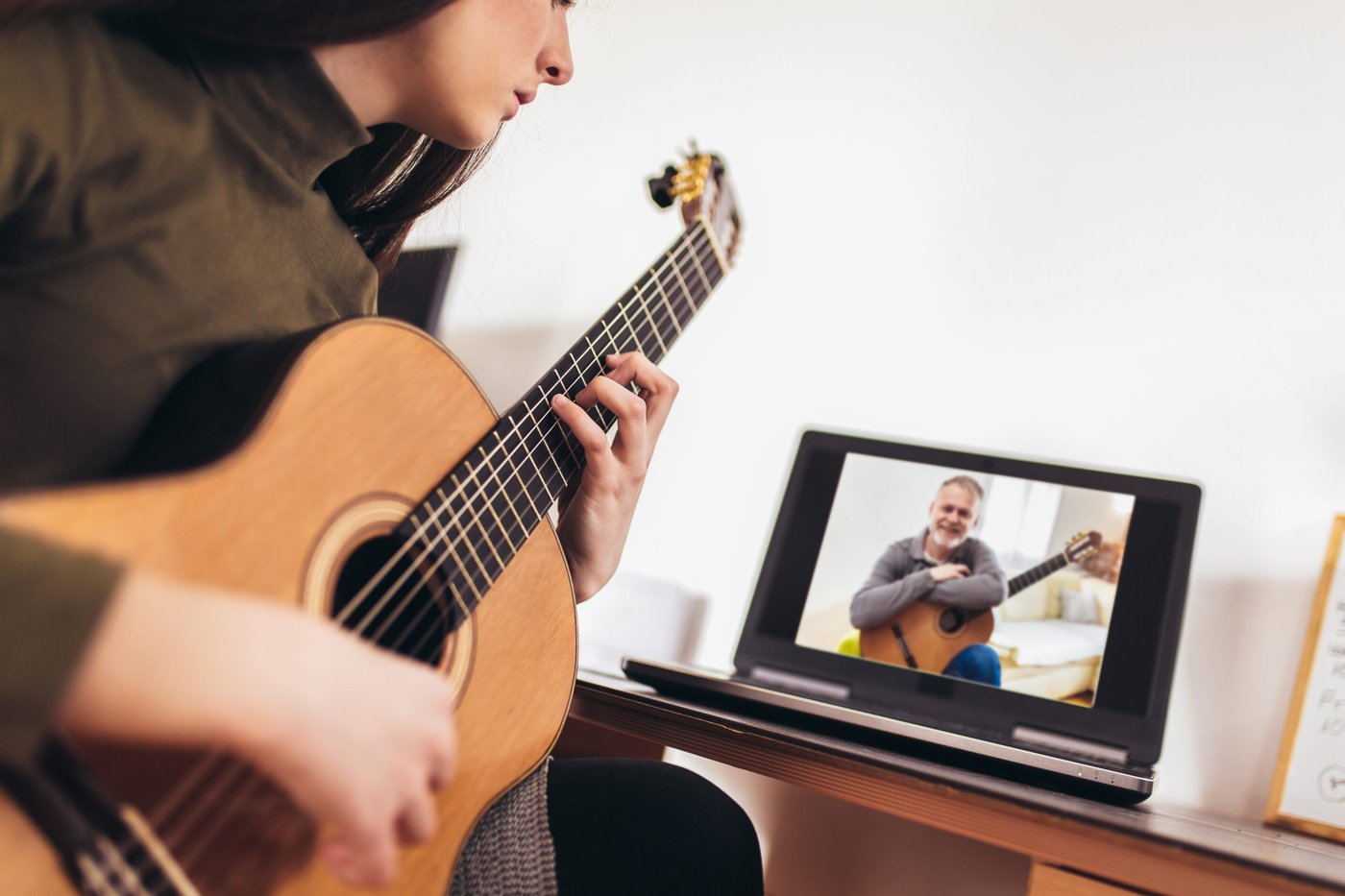 Frau mit Gitarre schaut sich ein Video-Tutorial an.