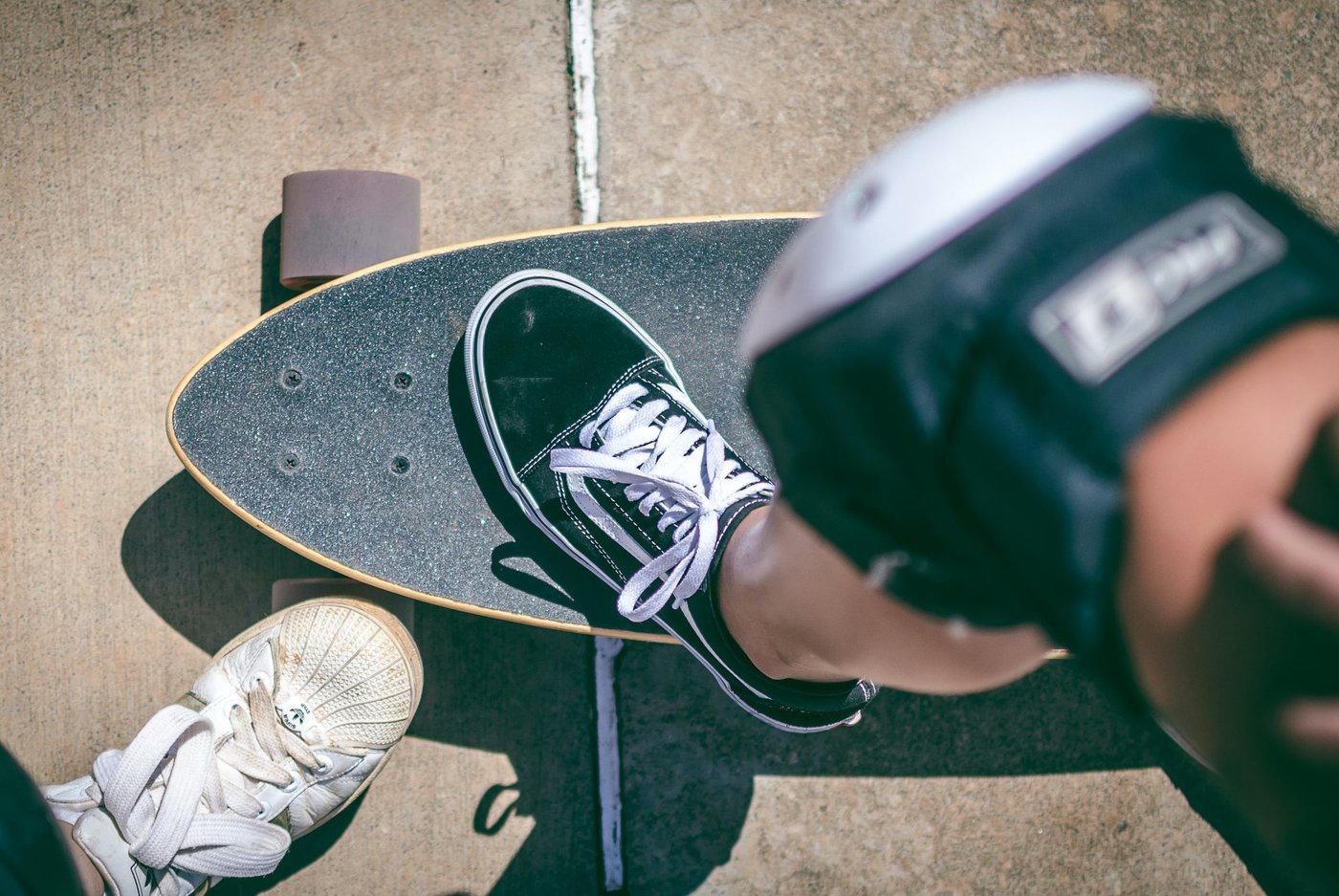 Person mit Knieschoner stellt ein Bein auf ein Skateboard