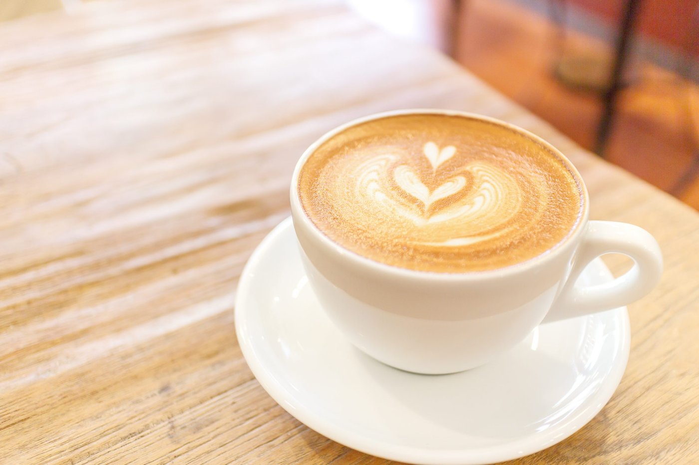Kaffeetasse mit Latte-Art auf einem Holztisch