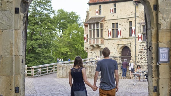 Besucher blicken über den Burghof auf die Hauptburg der Burg Vischering. Die imposante Burg liegt am Südkurs der 100-Schlösser-Route