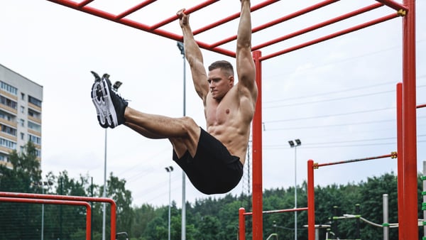 Junger Mann hängt an einem Gerüst in einem Calisthenics-Park