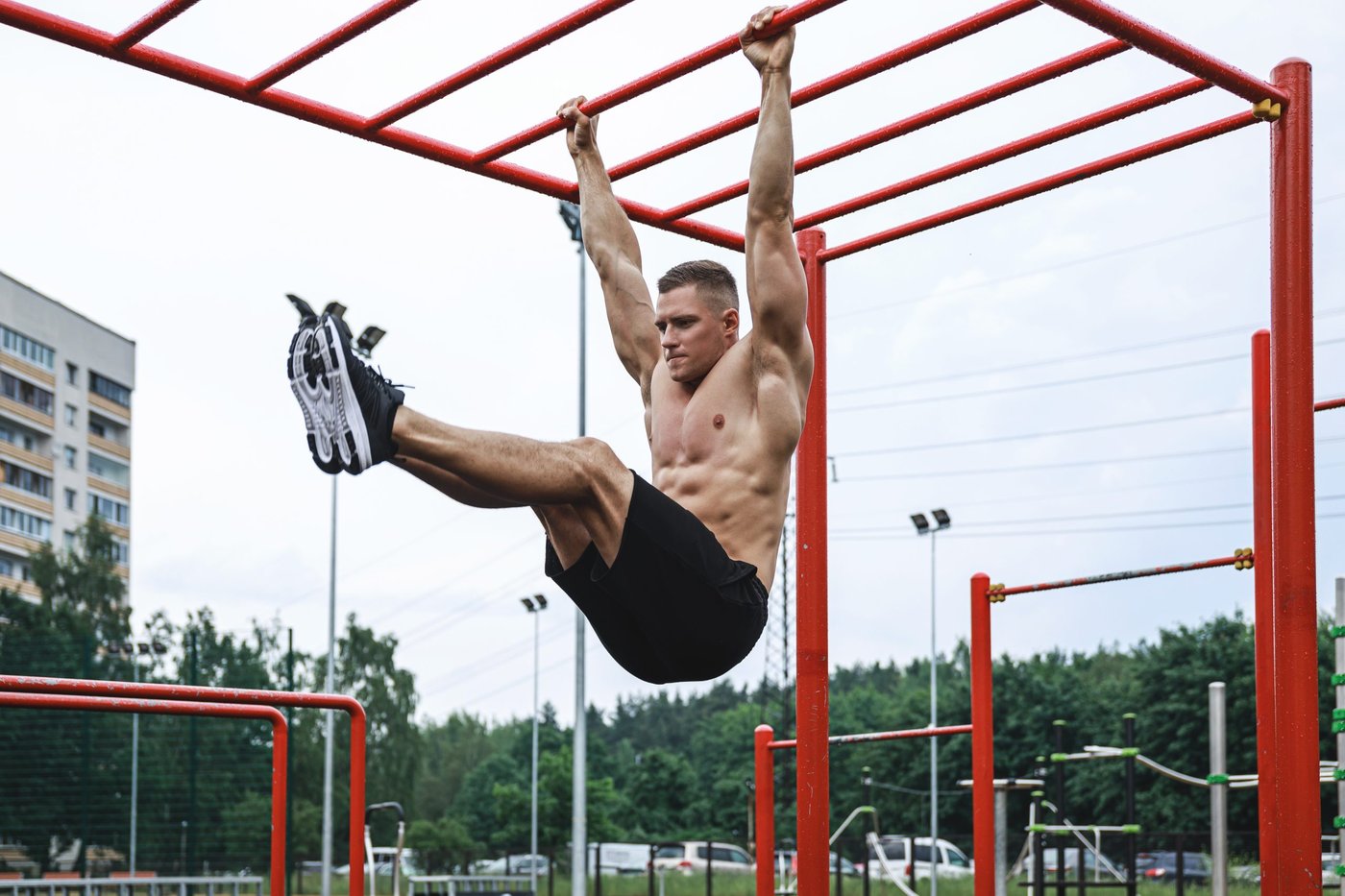 Junger Mann hängt an einem Gerüst in einem Calisthenics-Park