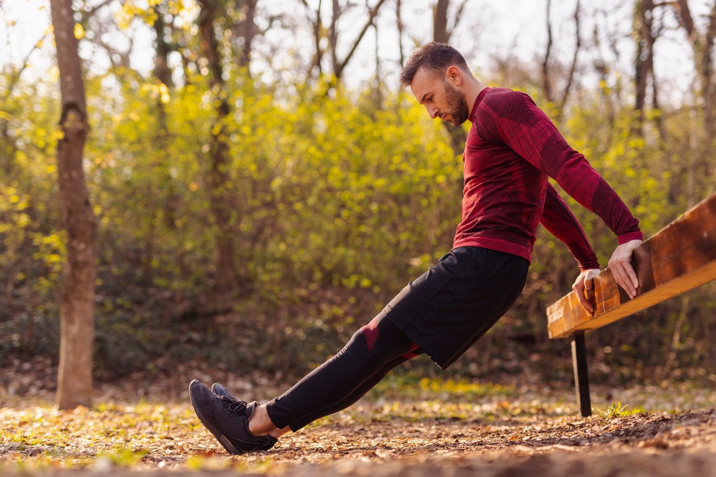 Mann macht Dips an einer Bank im Park