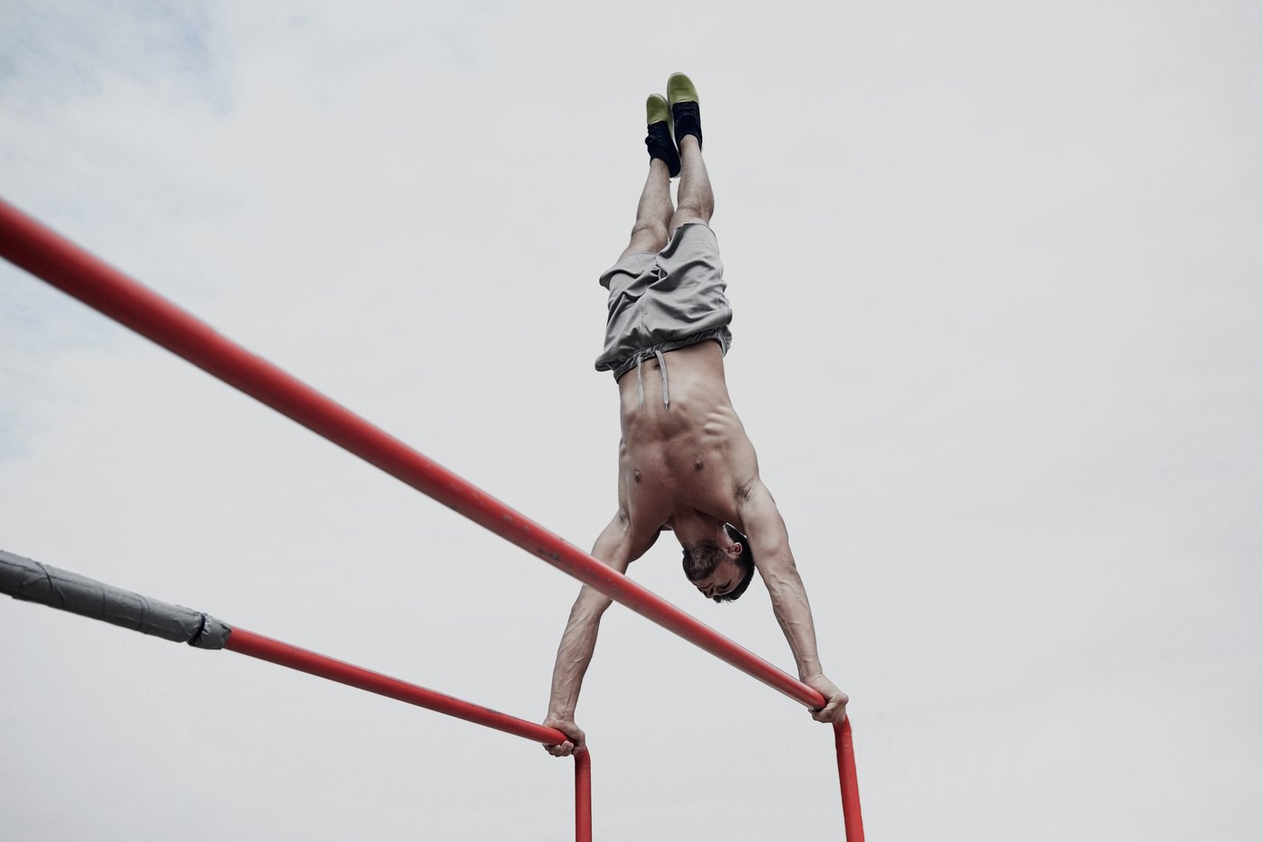 Mann macht einen Handstand auf einem Dipbarren