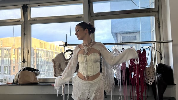 Frau im weißen Outfit vor einem Fenster.