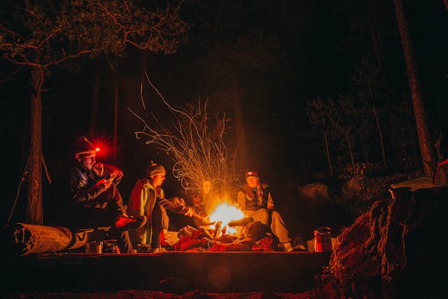 Eine Gruppe sitzt an einem offenen Lagerfeuer
