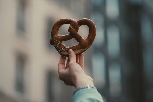 Eine Laugenbrezel wird in die Kamera gehalten