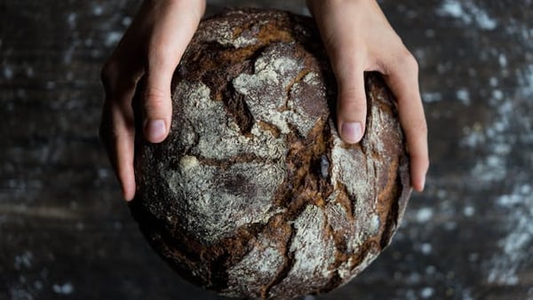 ein frisch gebackenes Brot wird von zwei Händen gehalten