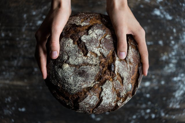 ein frisch gebackenes Brot wird von zwei Händen gehalten