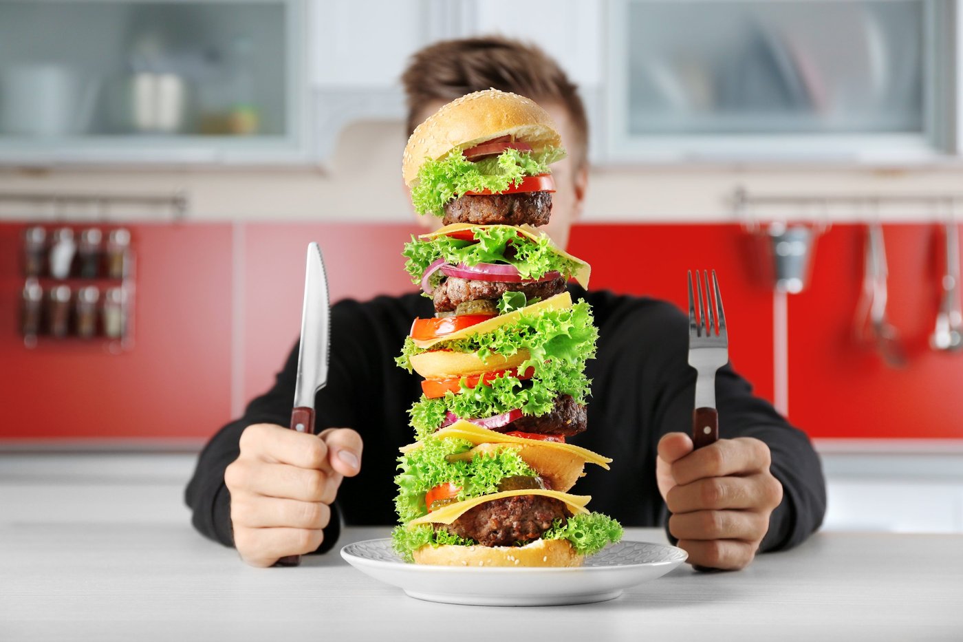 Mann hat großen Burger vor sich auf dem Teller