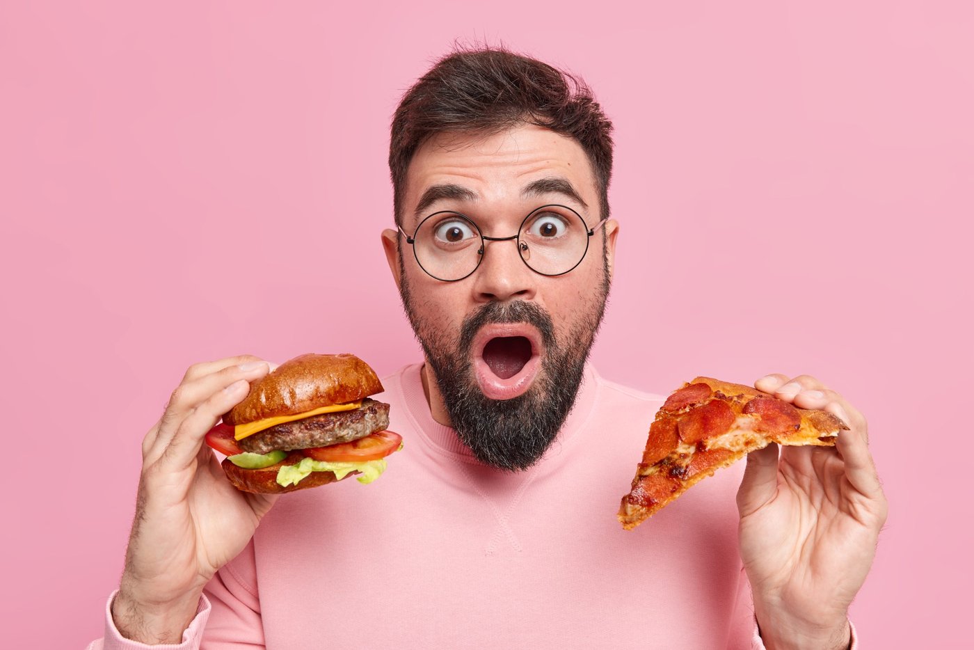 Mann hat Pizza und Burger in der Hand
