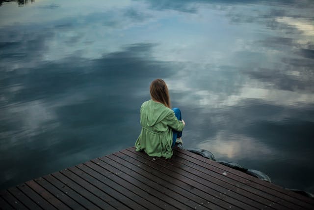 Frau sitzt allein am Wasser