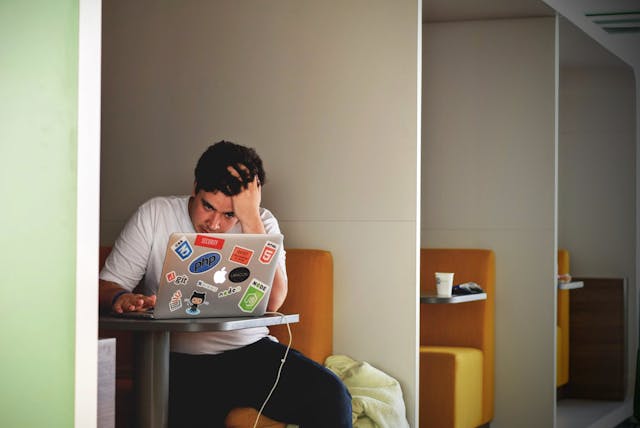Man sitzt gestresst vor seinem Laptop
