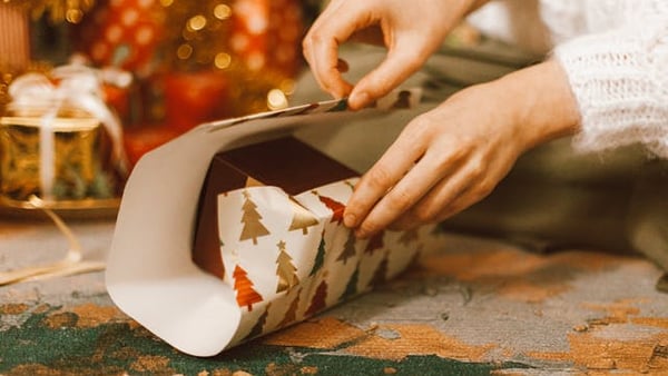 eine Frau packt ein Geschenk in Geschenkpapier