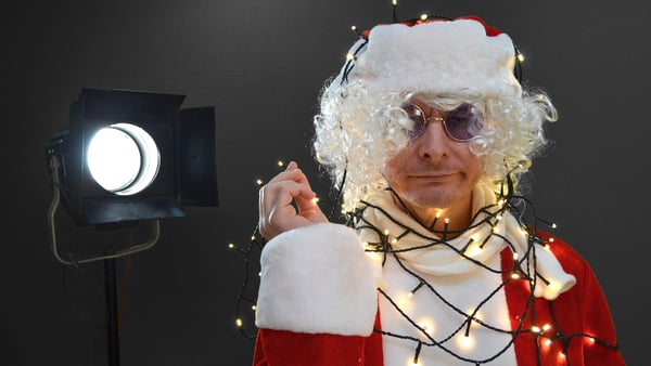 Mann im Weihnachtsmann-Kostüm und mit Lichertekette