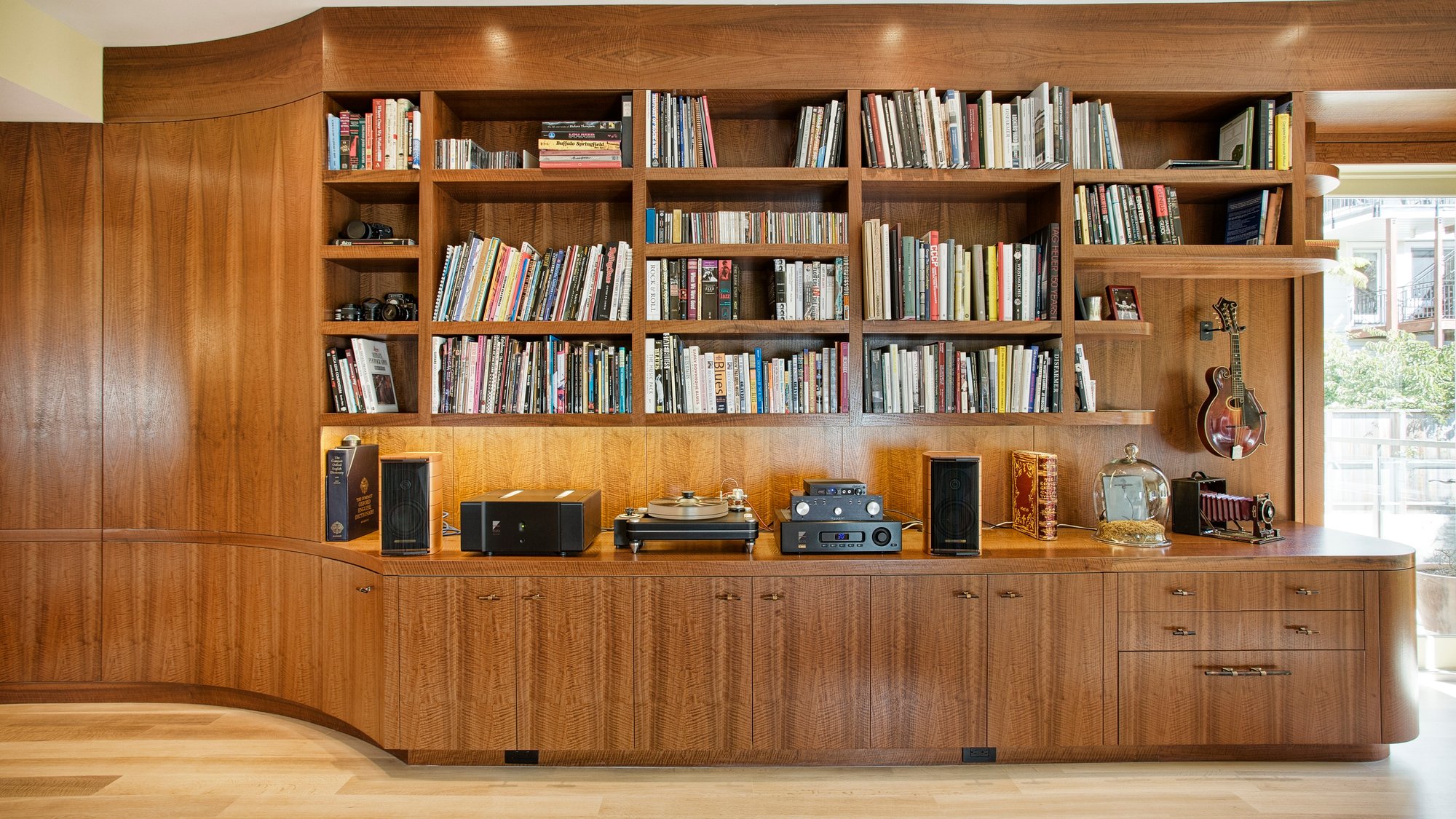 A modern space with a steel-framed fireplace, wood-paneled walls, minimalist art, and a sleek dining area.