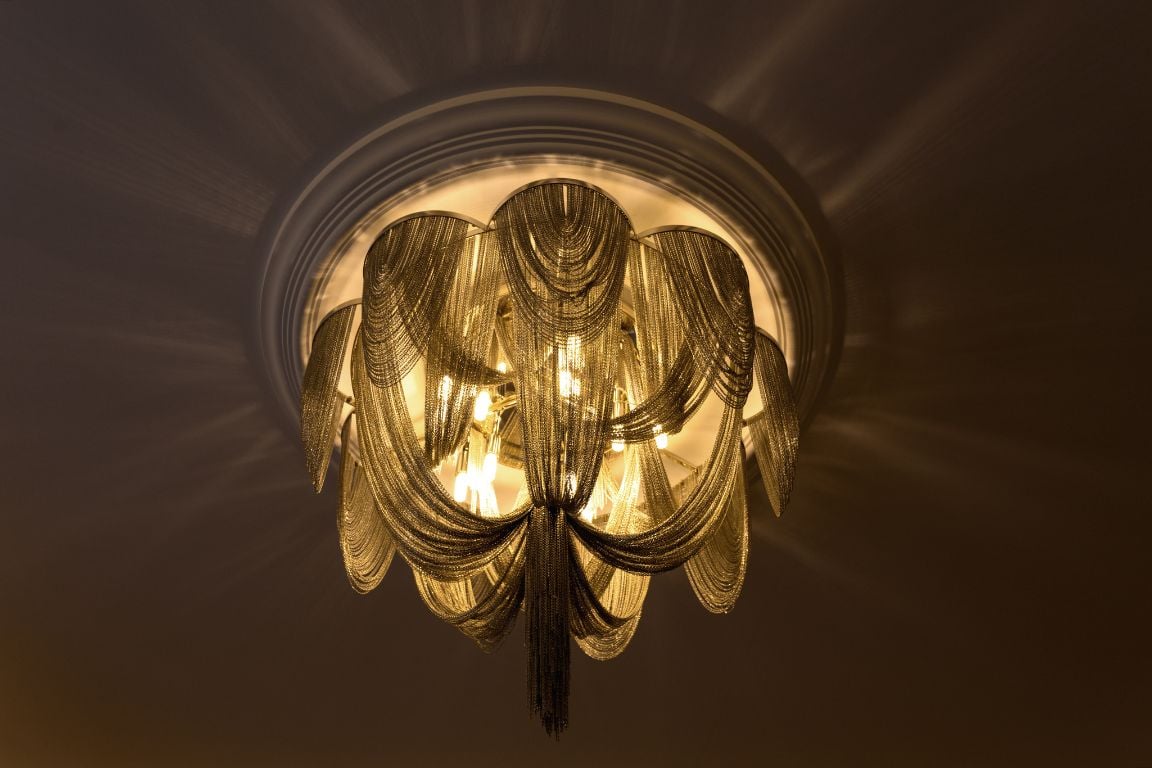 Luxurious chandelier with cascading gold chains casting elegant light patterns on the ceiling.