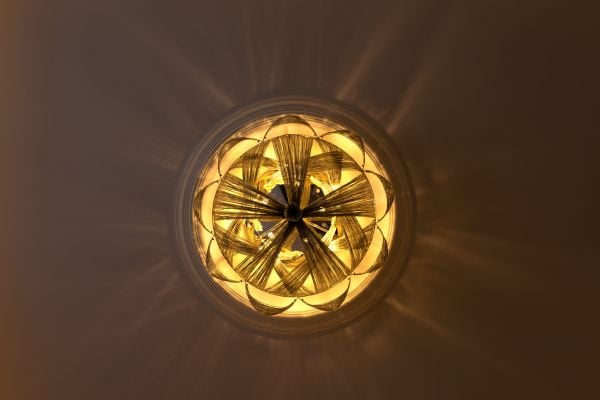 Close-up of a decorative golden light fixture casting intricate patterns on the ceiling