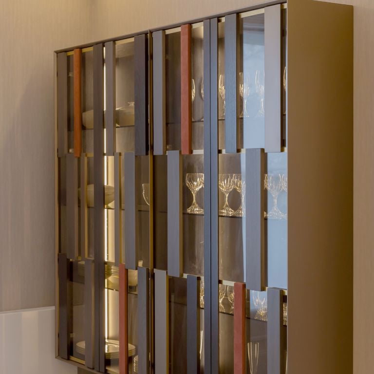 Stylish dining room storage cabinet with a mix of wood and glass, displaying elegant glassware.