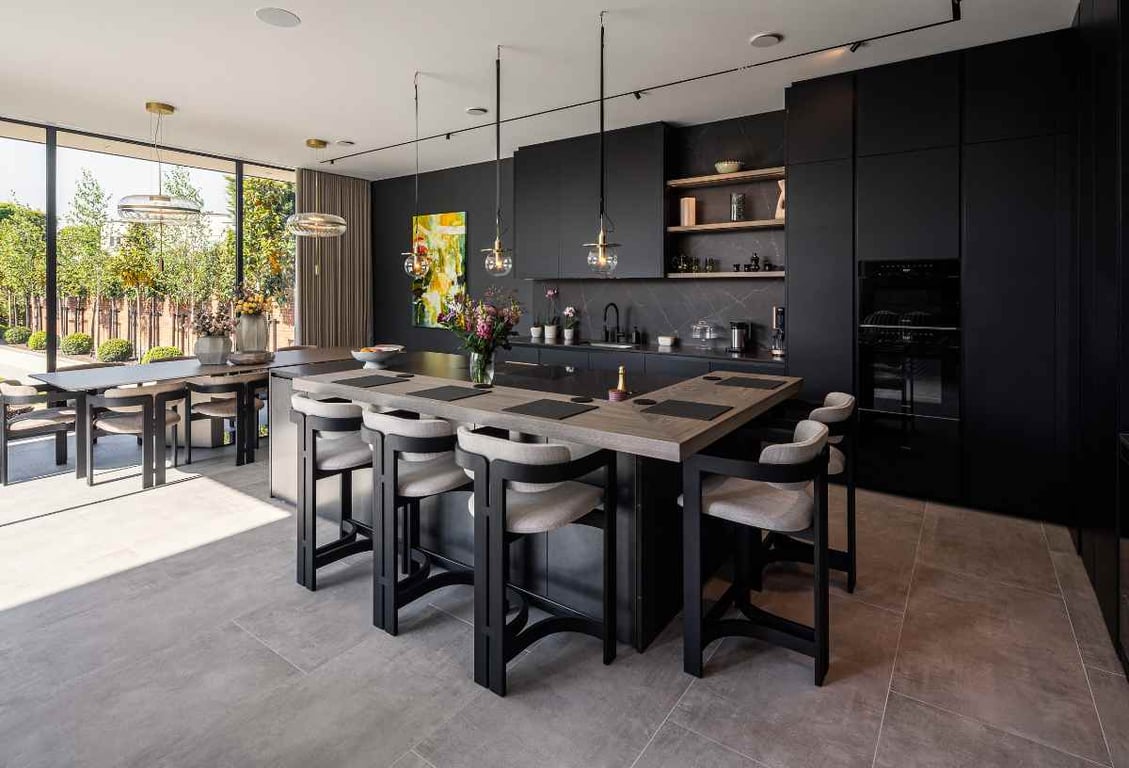Modern kitchen with a large countertop, bar stools, and floor-to-ceiling windows.