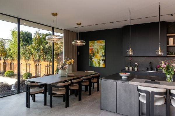 Modern kitchen with pendant lighting, dark cabinetry, and colorful artwork.