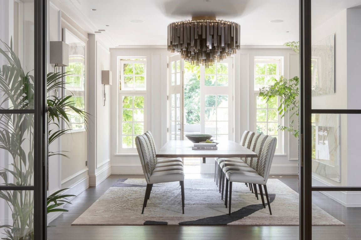 Elegant dining area with modern design, large windows, and statement chandelier.