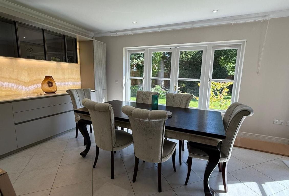 Dining area with elegant table, chairs, and large windows overlooking the garden.