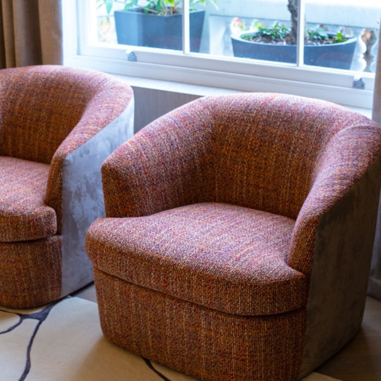 Two stylish accent chairs in a vibrant woven fabric, positioned by a window in a modern living room.