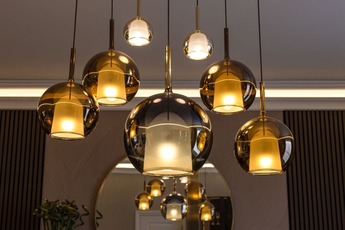 Elegant glass pendant lights with a warm glow hanging in a dining room.