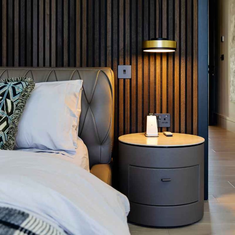 Bedroom with striped wooden wall panel, bedside lamp, and modern furniture.