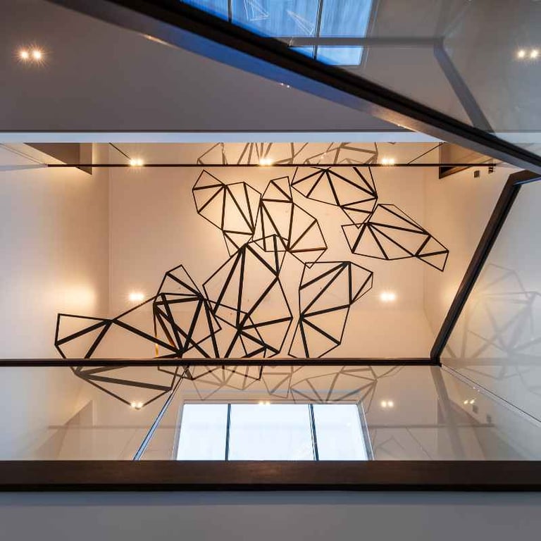 Geometric wall art installation in a modern home with a glass railing.