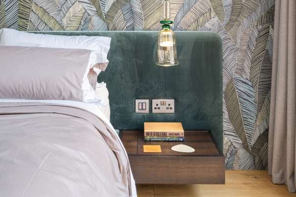Close-up of a bedside table with books, perfume bottles, and decorative items.
