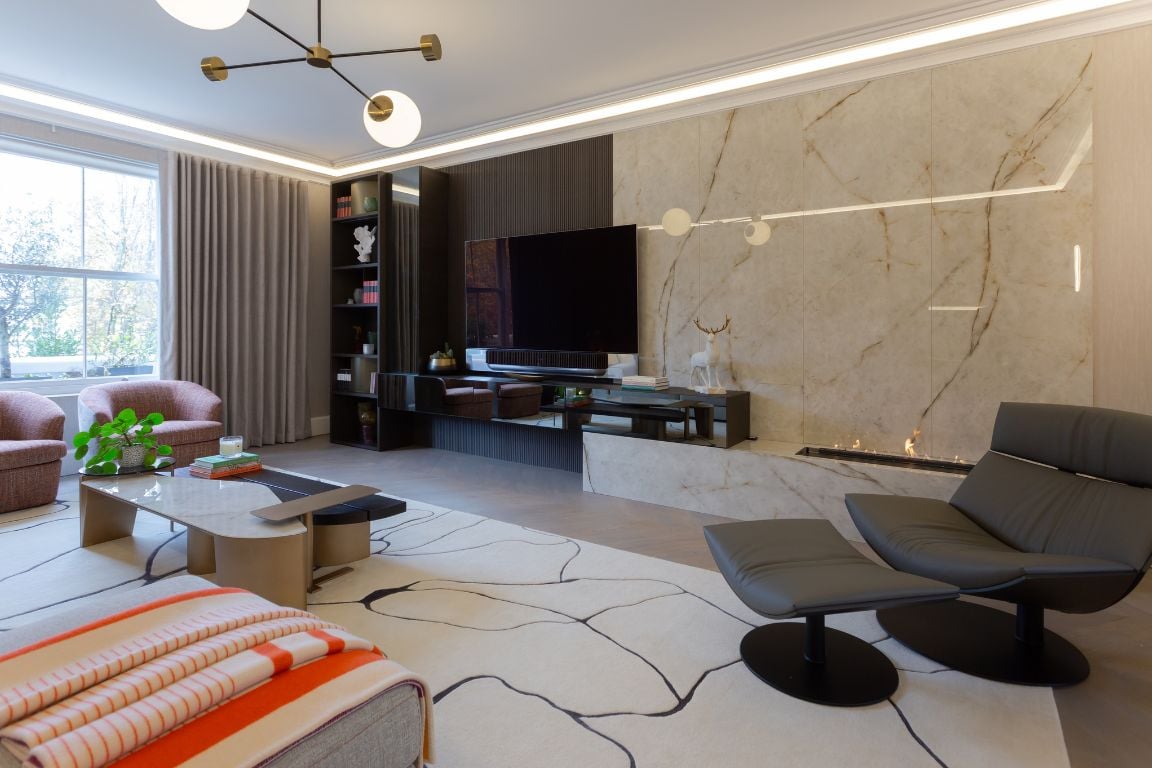 Sleek leather lounge chair with ottoman in a modern living room with a marble TV wall.
