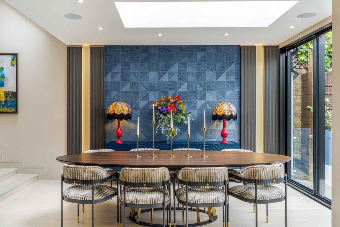 Modern dining area with a blue geometric wall, floral lamps, and a stylish dining table.