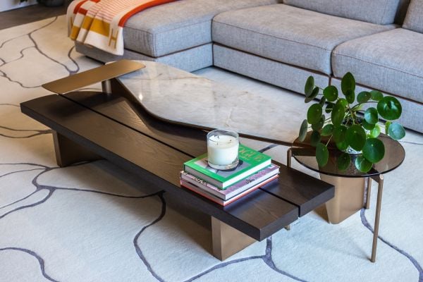 Contemporary coffee table with marble top, books, and a decorative plant in a modern living room.