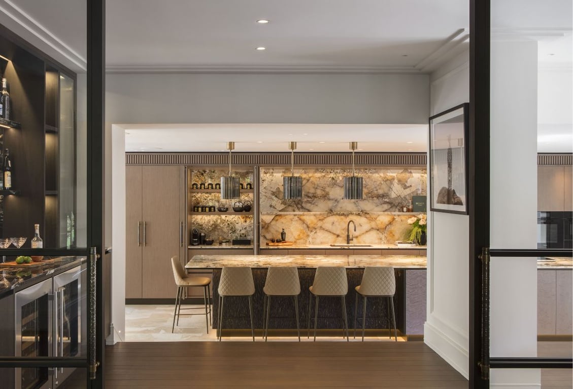 Modern kitchen with marble countertops, sleek cabinets, and barstools.