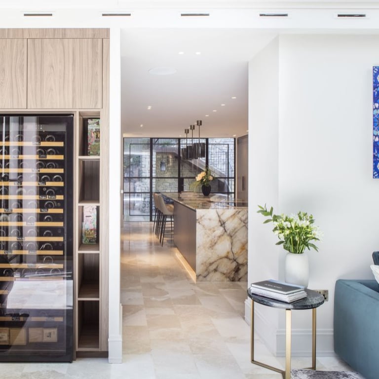 Modern kitchen with a wine fridge, marble island, and barstools.
