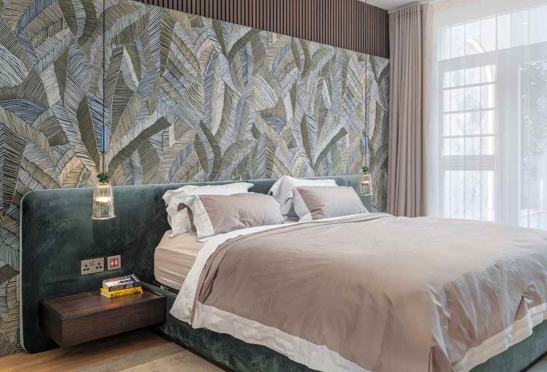 Bedroom with leaf-patterned wall and velvet bed frame.