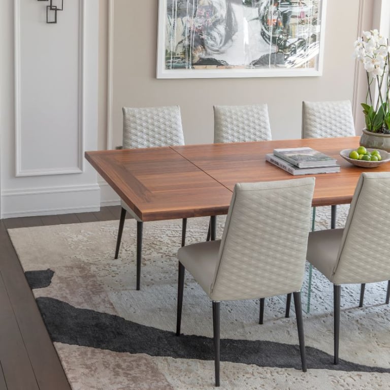 Elegant dining space with wood table, upholstered chairs, and chic decor.