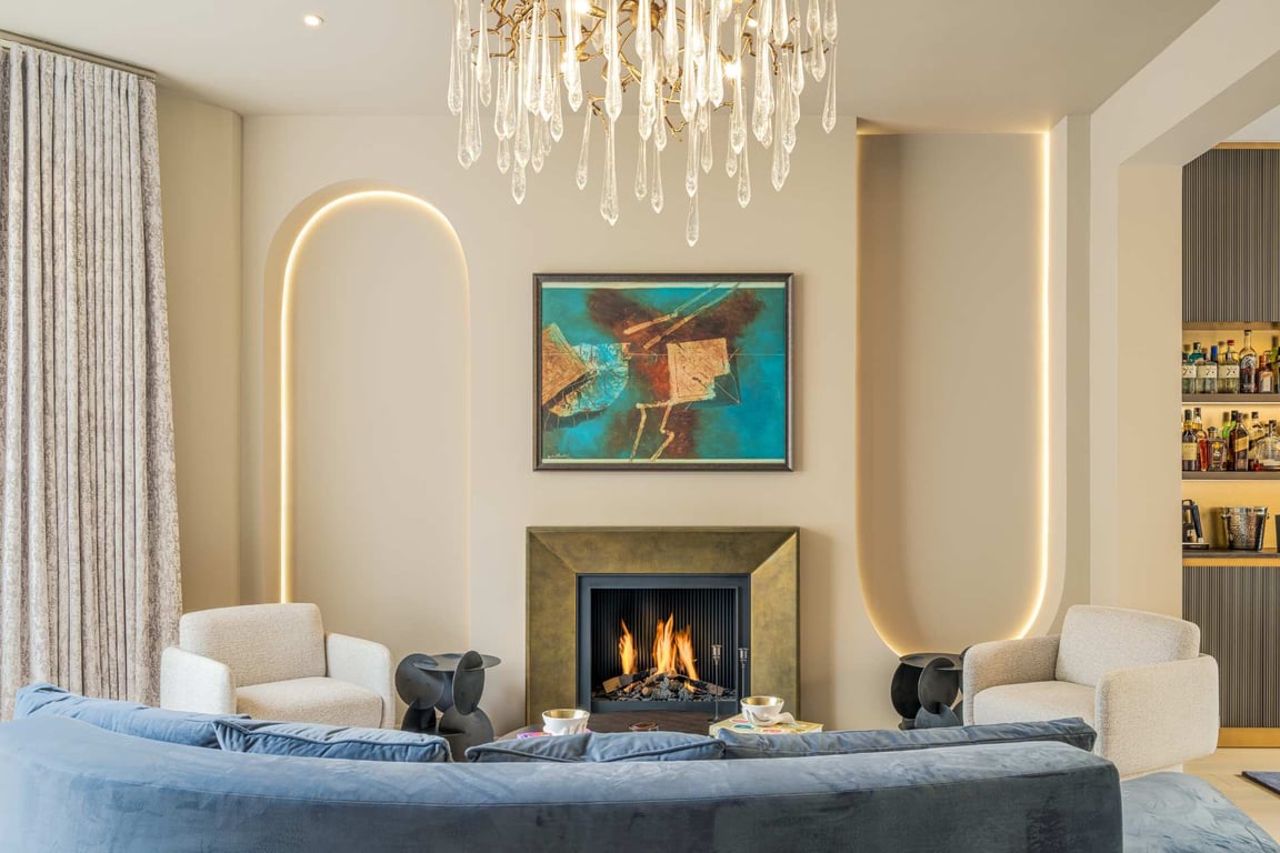 Living room with curved sofa, modern fireplace, art piece, and elegant lighting.