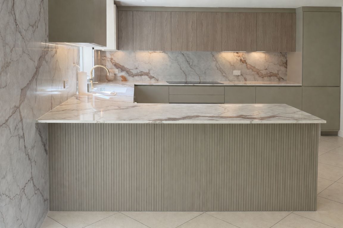 Contemporary kitchen featuring a marble countertop with taupe cabinetry and wood accents.
