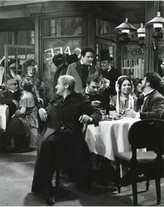 Seduti al tavolo Ivo Vinco, Gianni Maffeo, Mirella Freni, Gianni Raimondi; in piedi Adriana Martino e Rolando Panerai: nel secondo quadro dell'opera, gli amici festeggiano la vigilia di Natale al Caffè Momus.