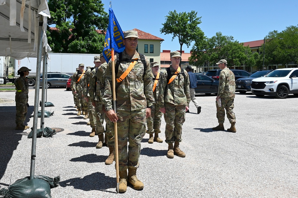 Air Force ROTC cadets march in formation carrying a detachment guidon during field training
