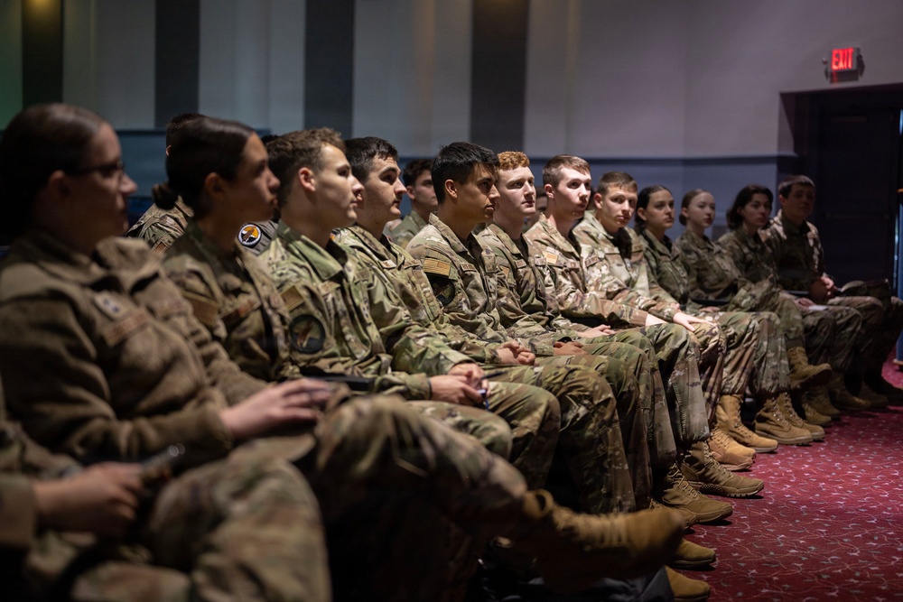 AFROTC cadets from a university detachment sit in an auditorium listening to a mission briefing during a base tour