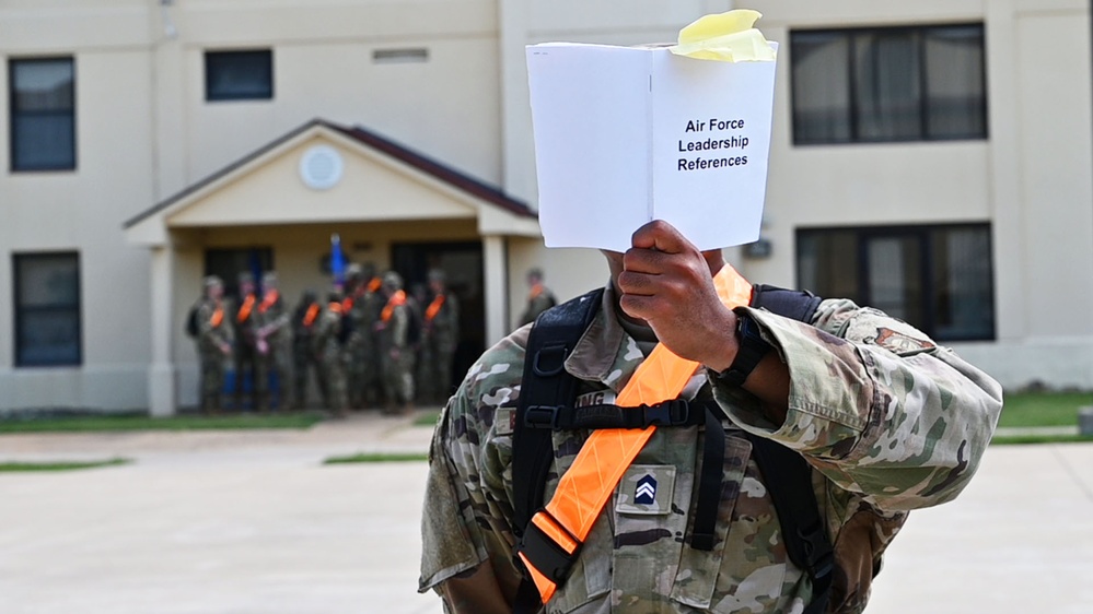 An AFROTC cadet holds up a booklet titled Air Force Leadership References during field training