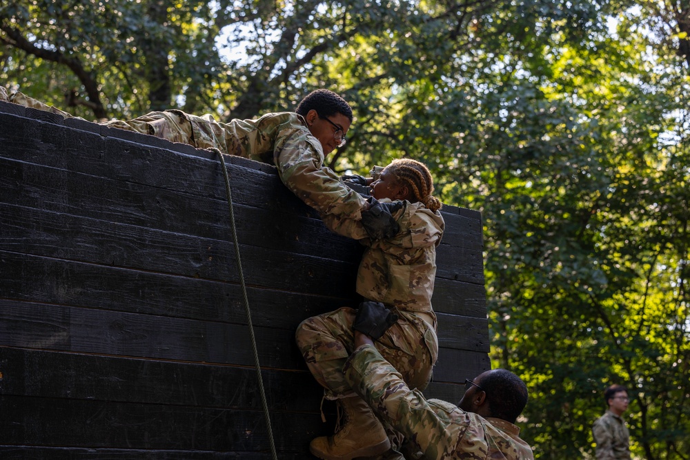 Army ROTC cadets working together through an obstacle on a teamwork course during summer training