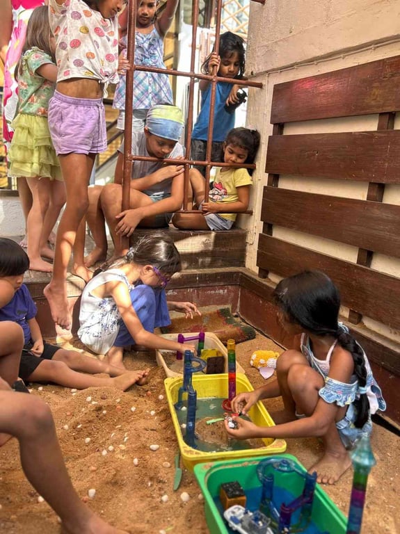 Two kids weaved in conversations and explorations about water and community to come up with a story of Two Villages during freeplay. Their friends watch as they tell the story