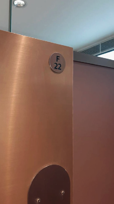 Cubicle identification signage, etched and PVD coated to match push plates, London Victoria. Image: Landolt + Brown. Signage to be mounted to push plate edge where practical.