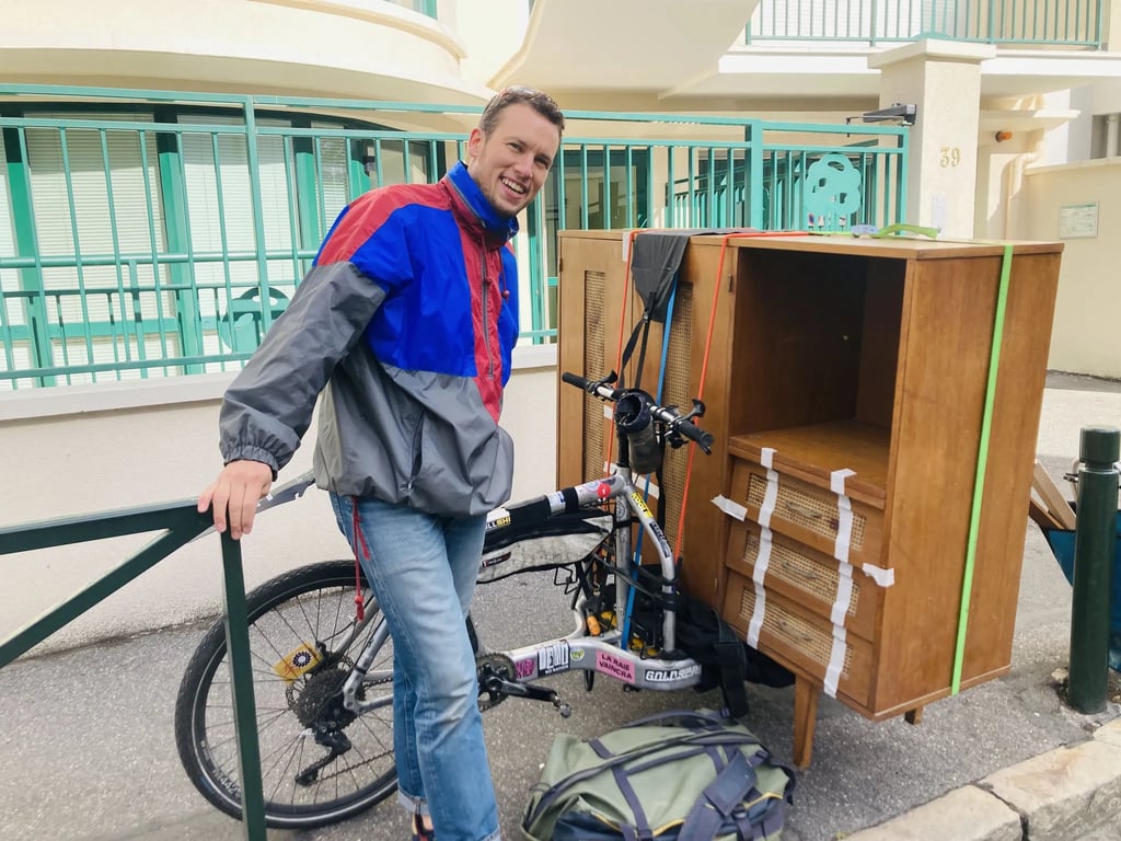 Vélo cargo biporteur de la marque Larry vs Harry sur lequel repose une commode avec cannage, dénichée par un particulier.